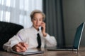 Selective focus portrait of busy middle-aged business woman multitasking in office, working online with laptop, talking Royalty Free Stock Photo