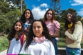 Selective focus portrait of a teenage student with curly hair wearing pink headphones on her neck with four girlfriends out of