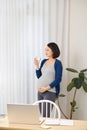 Selective focus of pregnant woman using laptop while working from home Royalty Free Stock Photo