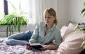 selective focus on a pretty blonde young woman lying in bed and reading a book. The concept of rest, education and time Royalty Free Stock Photo