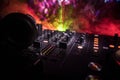 In selective focus of Pro dj controller.The DJ console deejay mixing desk at music party in nightclub with colored disco lights.