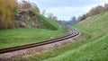 Selective focus railway track twists and turns between hills. Empty rounding and turning single track of railways