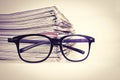 Selective focus on reading eyeglasses with stacking of newspaper Royalty Free Stock Photo