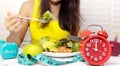 Selective focus of Red clcok which young woman Eating healthy breakfast for Intermittent fasting program for diet plan-Healthy Royalty Free Stock Photo