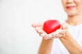 Selective focus of red heart held by smiling female nurse`s both hand, representing giving all effort to deliver high quality