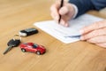 Focus of red toy car near car key and car dealer holding pen near contract Royalty Free Stock Photo