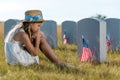 Focus of sad child sitting and looking at headstones with american flags
