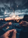 Selective focus of several hands holding fireworks at dusk. creative background template.