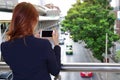 Selective focus and shallow depth of field. Back view of woman taking a photo of traffic car in city with mobile smart phone Royalty Free Stock Photo