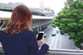 Selective focus and shallow depth of field. Back view of woman taking a photo of traffic car in city with mobile smart phone Royalty Free Stock Photo