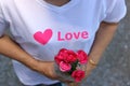 Selective focus and shallow depth of field of a beautiful bouquet of red roses is held on hand of middle aged woman with white shi Royalty Free Stock Photo