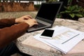 Selective focus and shallow depth of field of hands of business person is typing a laptop with blank screen , charts and mobile ph Royalty Free Stock Photo