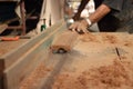 Selective focus and shallow depth of field. A piece of wood is being shaved on a router table by hands of carpenter in carpentry w