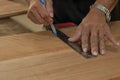 Selective focus and shallow depth of field. Ruler taking measurement on a wooden plank with hand of senior carpenter in workshop