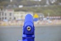 Selective focus shot of a blue telescope with a blurred lake and buildings in the background Royalty Free Stock Photo