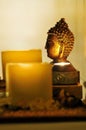 Selective focus shot of a Buddha statue with burning candles around it