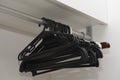 Selective focus shot of a bunch of black clothes hangers hanging on a closet rod