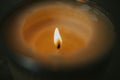 Selective focus shot of a candle flame burning a hole in the wax of a scented candle