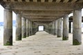 Selective focus shot of concrete pillars underneath a pier at the beach Royalty Free Stock Photo