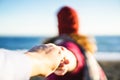 Selective focus shot of a couple holding hands with female leading to the beach