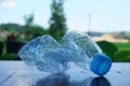Selective focus shot of a crushed water bottle on a wooden surface with a blurred background Royalty Free Stock Photo