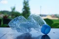 Selective focus shot of a crushed water bottle on a wooden surface with a blurred background