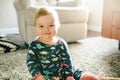 Selective focus shot of a cute Caucasian baby sitting on a soft rug indoors and smiling Royalty Free Stock Photo