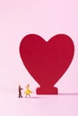 Selective focus shot of cute dancing figurines and a red heart on the background