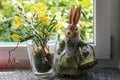 Selective focus shot of a cute dressed easter bunny beside a vase with a yellow flower
