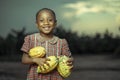 Selective focus shot of a cute happy African-American child with fruits in hands