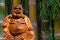 Selective focus shot of fat buddha statue with bamboos background