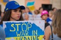 Selective focus shot of a female demonstrator holding Stop war in Ukraine placard