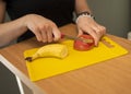 Selective focus shot of a female hand cutting apple and banana on a yellow cutting board Royalty Free Stock Photo