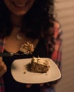 Selective focus shot of a female holding a plate with a piece of delicious cake