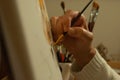 Selective focus shot of a female's hand painting on canvas with a paintb