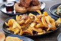 Selective focus shot of French fries with melted cheese and sliced sausage on a wooden table Royalty Free Stock Photo