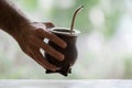 Selective focus shot of a hand holding a calabash mate cup with straw