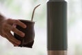 Selective focus shot of a hand holding a calabash mate cup with straw - yerba mate tea infusion