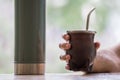 Selective focus shot of a hand holding a calabash mate cup with straw