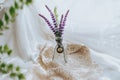 Selective focus shot of lavender plants in a small transparent vase with a necklace