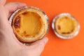 Selective focus shot of a man holding an egg tart with a color background behind