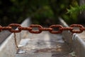 Selective focus shot of a massive rusty iron chain over a rural irrigation canal Royalty Free Stock Photo