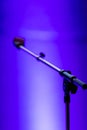 Selective focus shot of a microphone standon a bright blue background