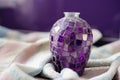Selective focus shot of a purple mosaic vase on a soft towel