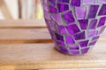 Selective focus shot of a purple mosaic vase on a wooden surface