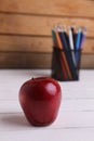 Selective focus shot of a red apple with colored pencils in a pencil holder Royalty Free Stock Photo