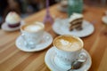 Selective focus shot of two cups of cappuccino coffee with foam on a wooden table