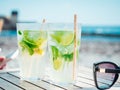 Selective focus shot of two glasses of mojitos and black sunglasses isolated on a table