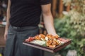 Selective focus shot of waiter's hand serving Spanish appetizer on wooden table in a restaurant
