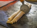 Selective focus shot of a wheel pizza cutter cutting a raw dough Royalty Free Stock Photo